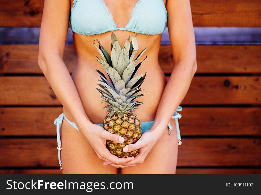 Woman Wearing Teal Bikini Holding Pineapple Fruit