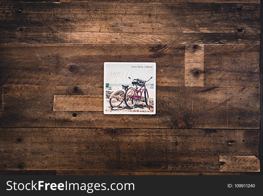 Two Assorted Bicycles Illustration on Brown Wooden Surface