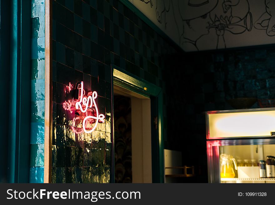 Less Neon Sign Mounted on Glass Board Near Open Window and Glass Display Rack