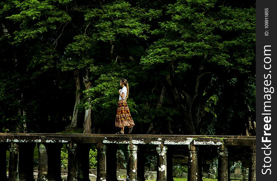 Woman Walking on Bridge Surrounded by Trees