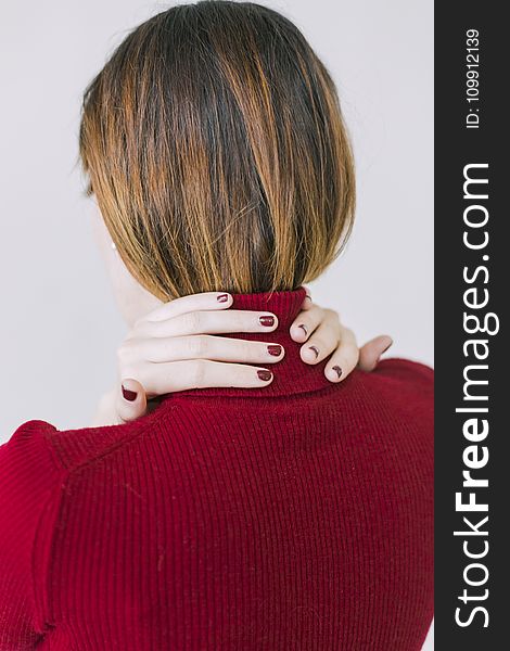Woman in Red Turtle-neck Shirt Touching Her Neck