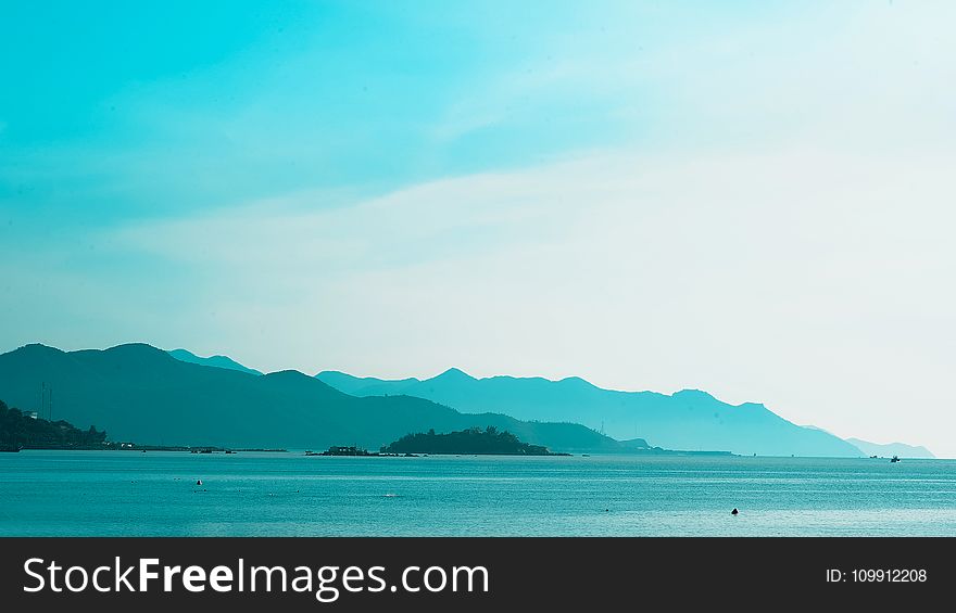 Silhouette of Mountain Near the Body of Water Photo in Daytime