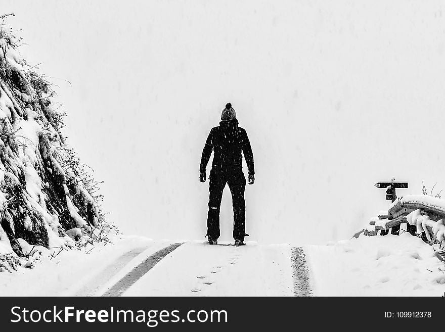 Man Standing on White Snow Covered Ground Beside Mountain