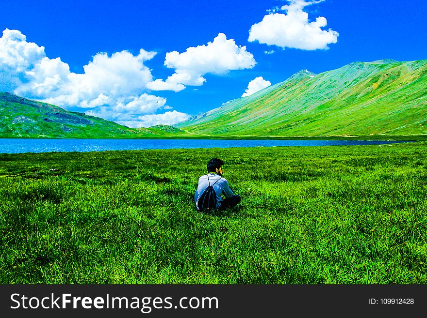 Boy Sitting on Green Grass Field