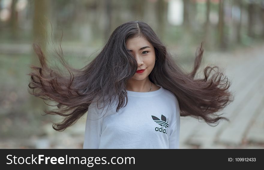 Woman With Long Hair Waving On Air And Wearing White Adidas Shirt