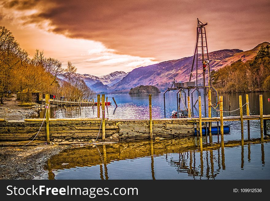 Brown Wooden Bridge Near Mountains and Body of Water