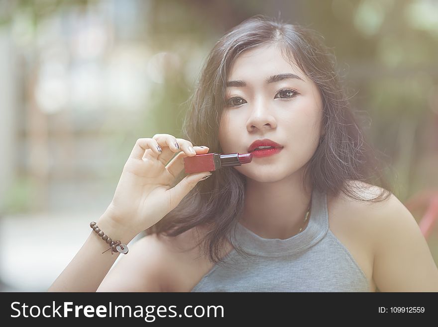 Woman Wearing Gray Halter-neckline Top Holding Red Lipstick