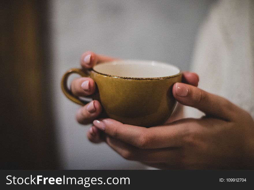 Person Holding Yellow Ceramic Cup