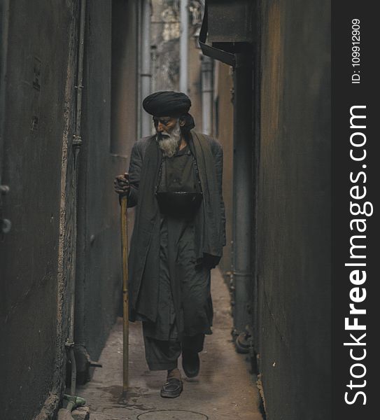 Photo of an Old Man Walking in the Alley