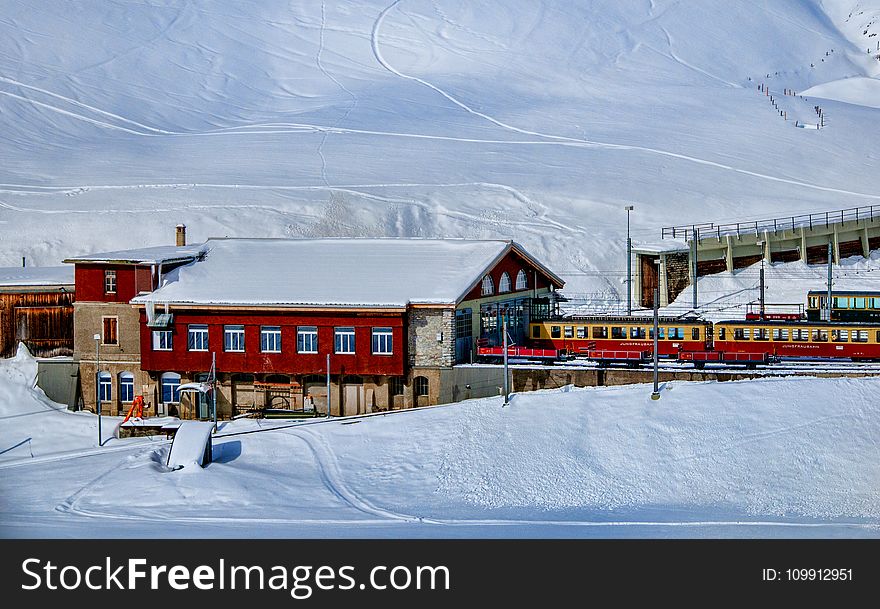 Yellow and Red Train Beside Snowy Mountain