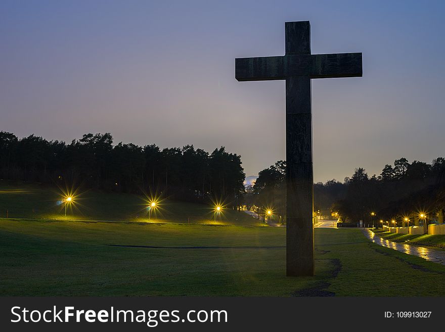 Brown Cross Statue on Green Grass Field With Turned on Light during Nighttime