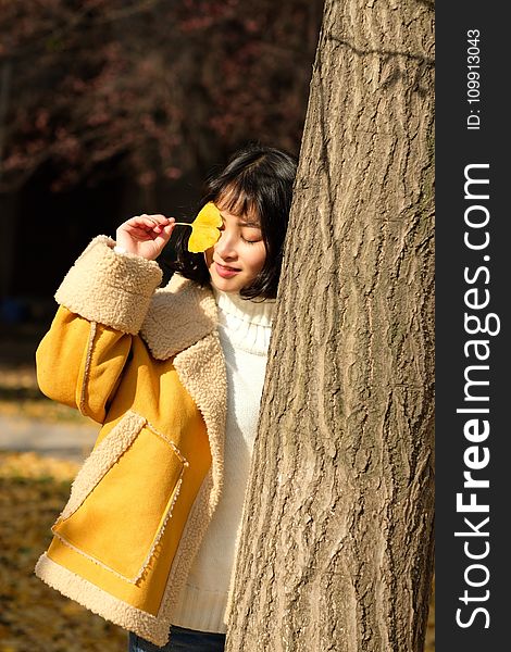 Woman Wearing Yellow Jacket Holding Yellow Leaf