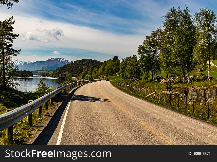 Brown Asphalt Road Beside Lake