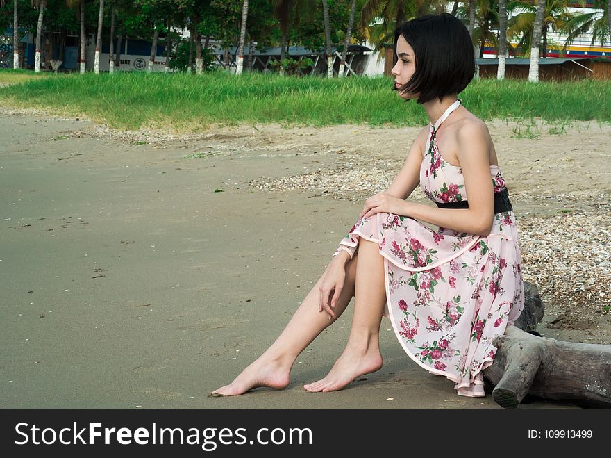 Woman In Pink Floral Halter Dress Seating In Driftwood