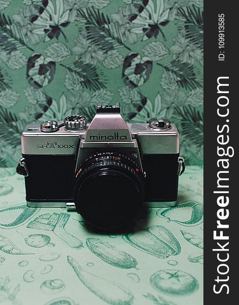 Black and Gray Film Camera on Green Floral Textile