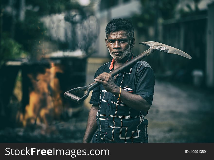 Depth of Field Photography of Man in Black Shirt Holding Shovel