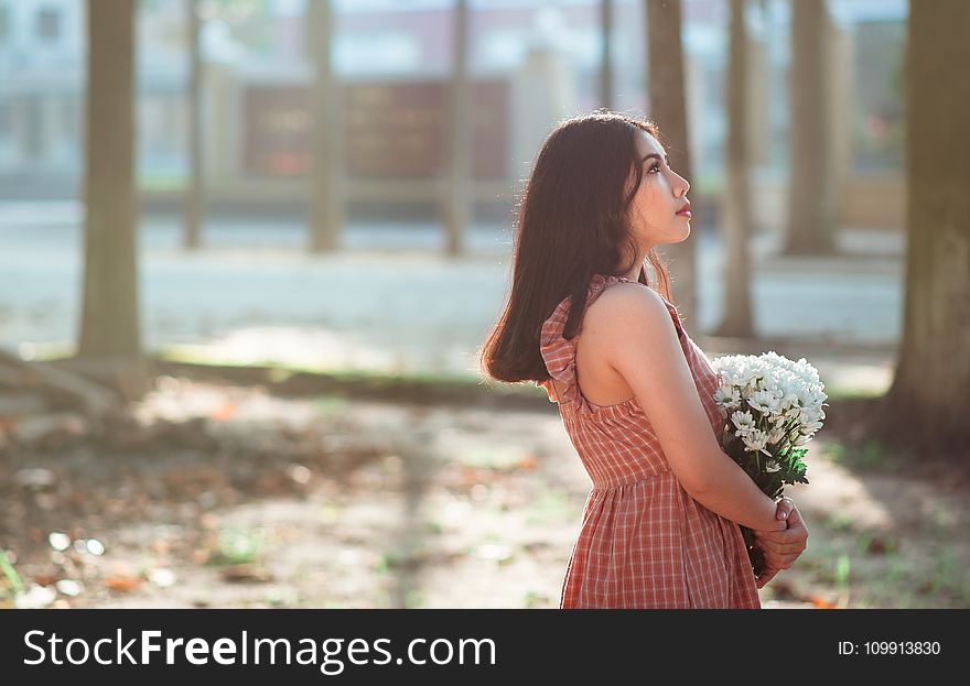 Woman Wearing Brown Sleeveless Dress Carrying White Flower Bouquet