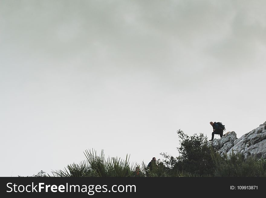 Person On Rocky Mountain Under White Cloudy Sky