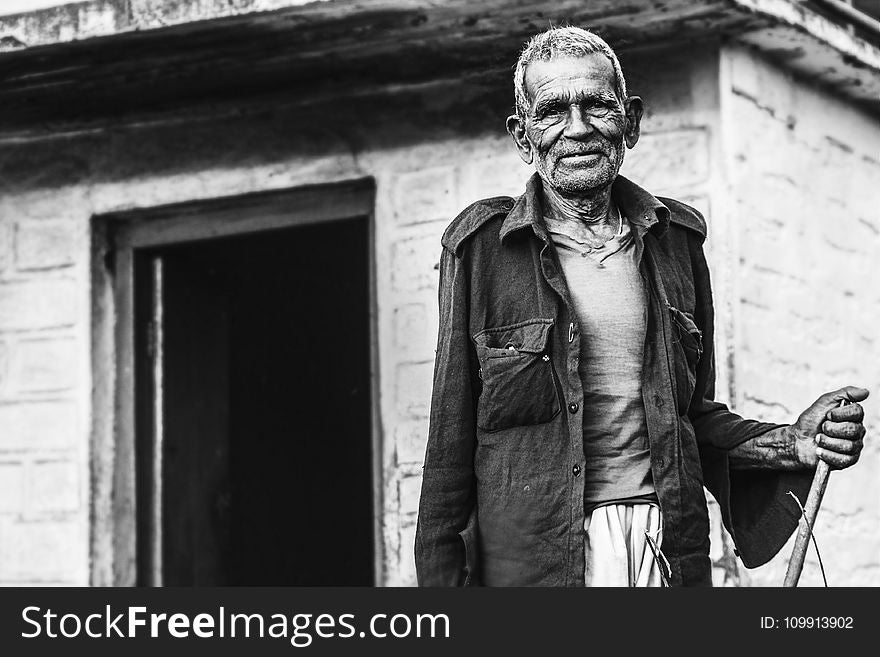 Man Wearing Button-up Shirt Standing Near Concrete House Greyscale Photo