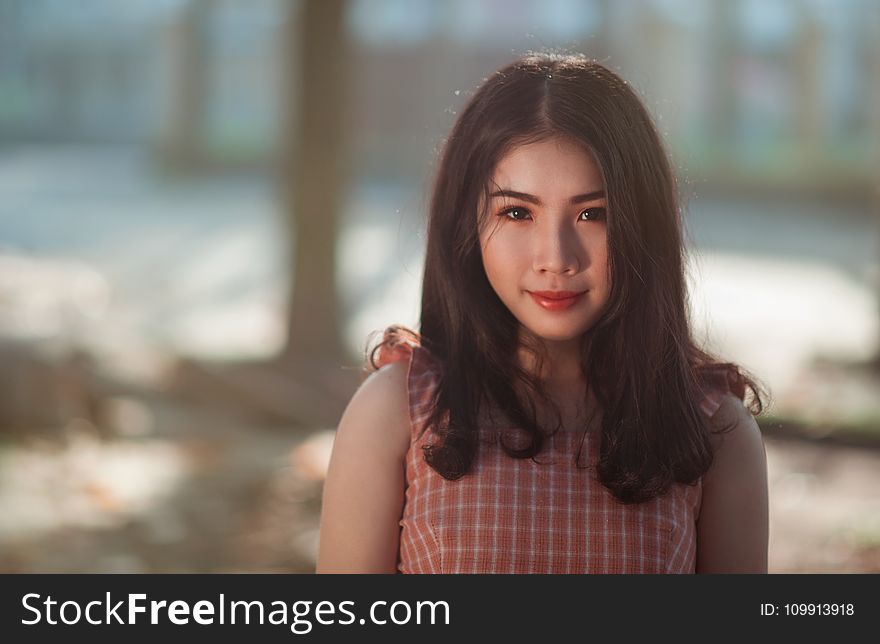 Selective Focus Photography Of Woman With Pink And White Sleeveless Top Standing Behind Tree Trunk