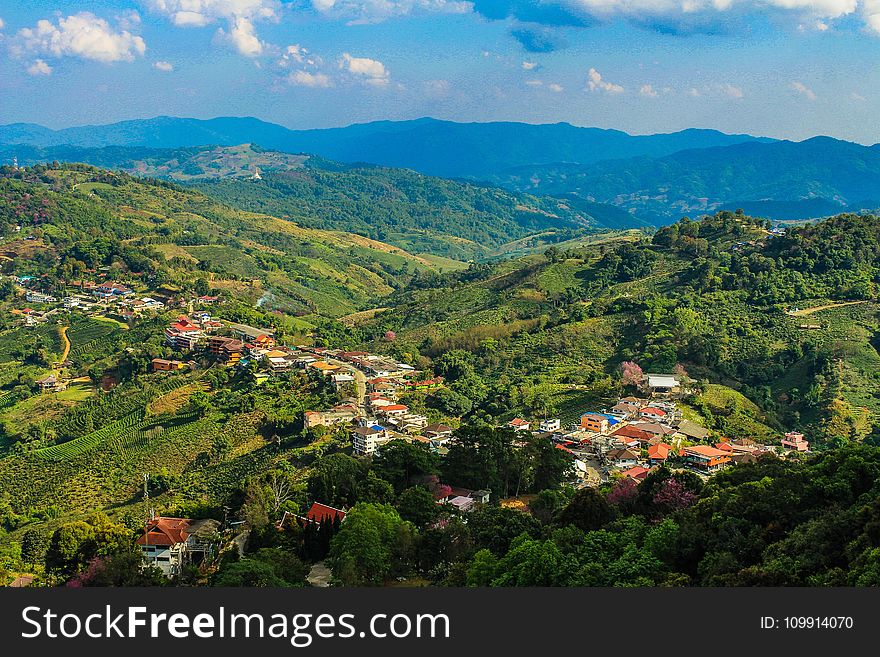 Aerial Photo of City Buildings Beside Green Mountains Under Cloudy Sky