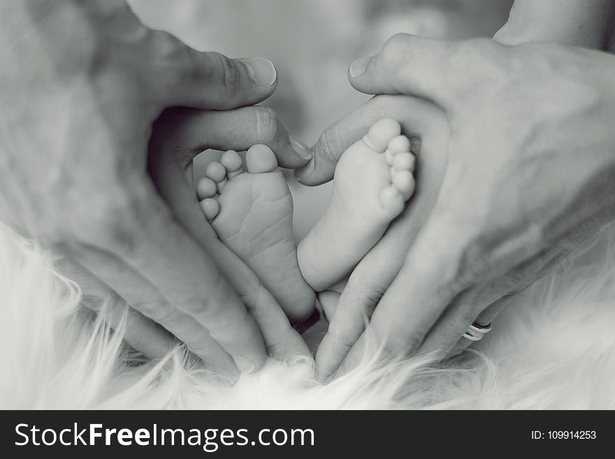 Grayscale Photo of Baby Feet With Father and Mother Hands in Heart Signs