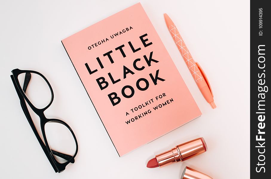 Little Black Book Surrounded With Pink Click Pen, Red Lipstick, and Black Wayfarer Eyeglasses