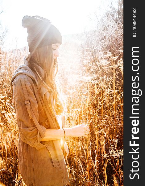 Woman in Black Beanie Standing Next to Tall Grass