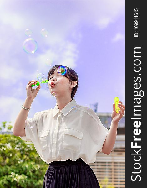 Photo of Woman in White Blouse Playing With Bubbles