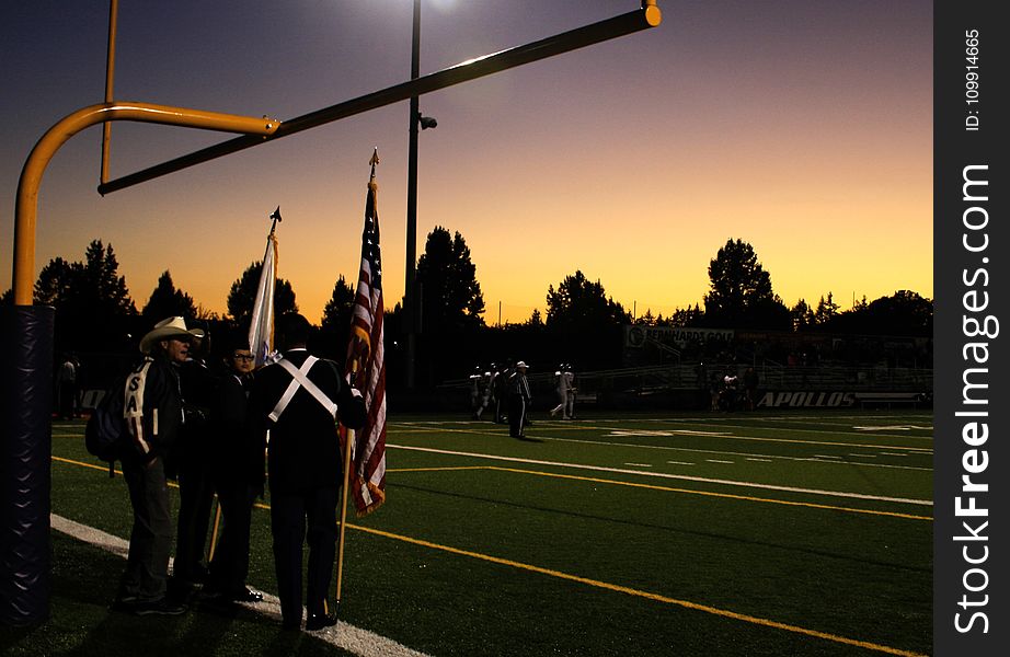 Four People Standing Under on Football Goal during Sunrise