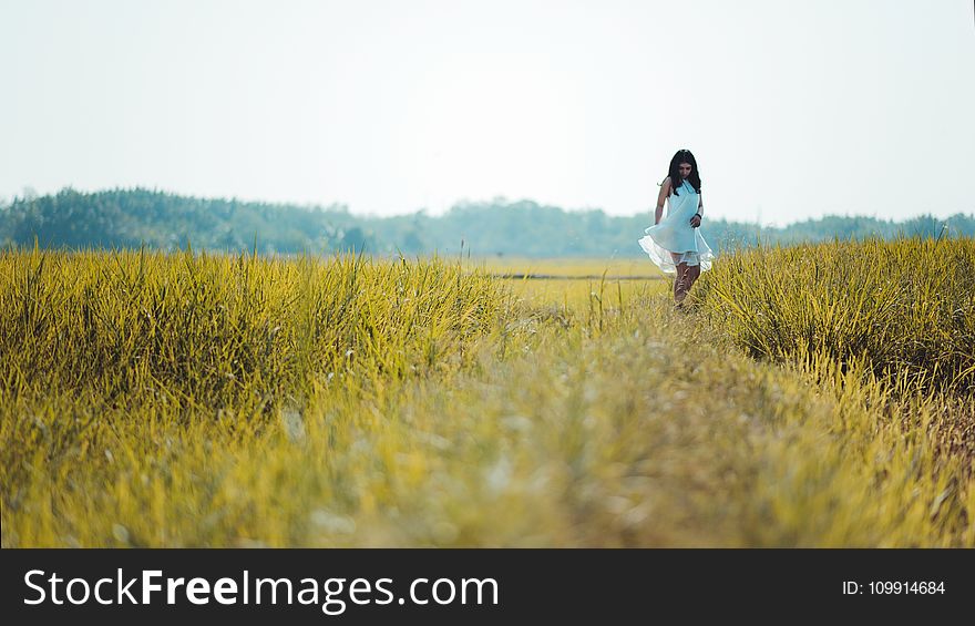 Depth Of Field Photography Of Woman Wearing White Sleeveless Dress Standing On Green Grass Field