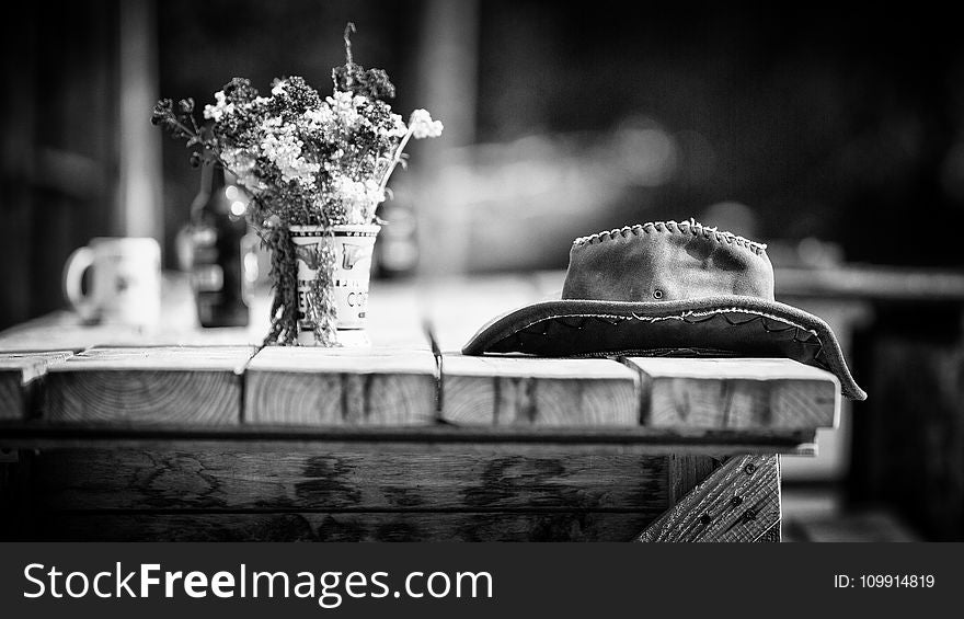 Grayscale Photography of Hat on Wooden Table