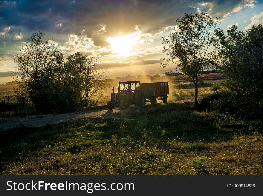 Tractor With Trailer Under Cloudy Skies during Day