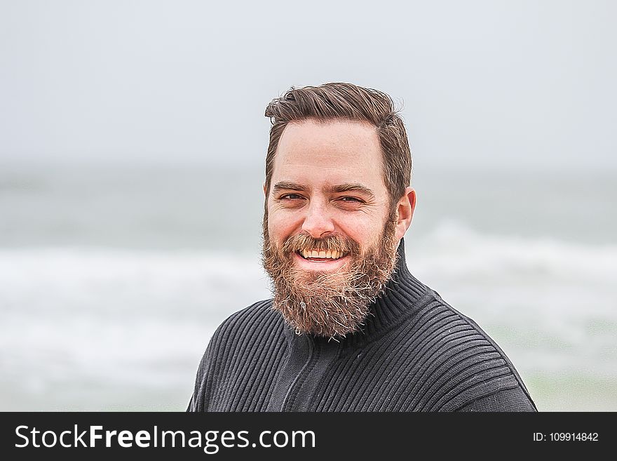 Man Wearing Black Zip-up Jacket Near Beach Smiling At The Photo