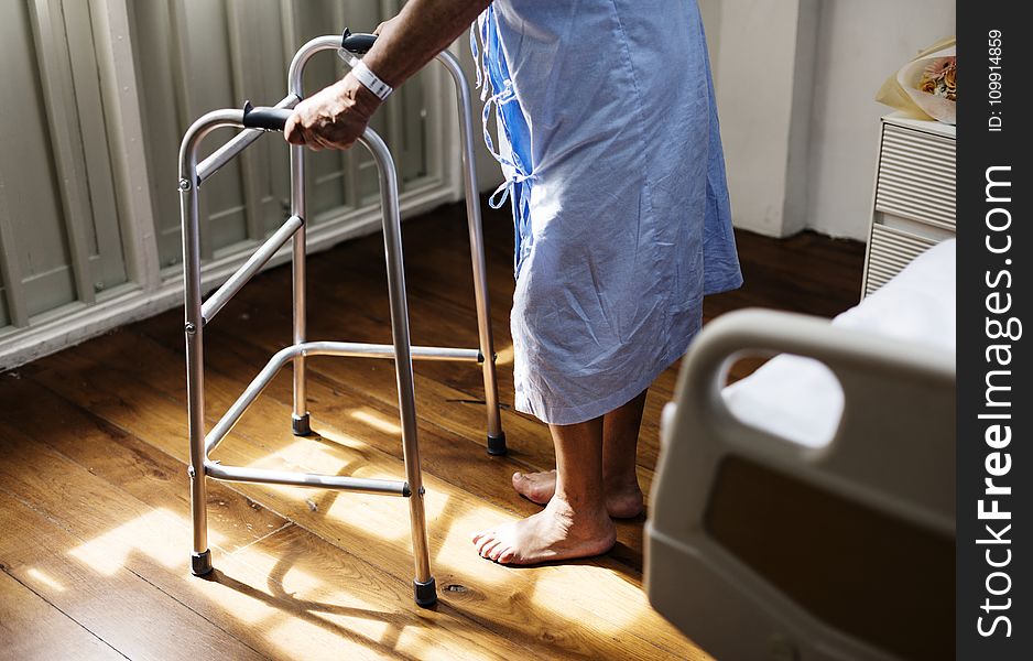 Person in Hospital Gown Using Walking Frame Beside Hospital Bed