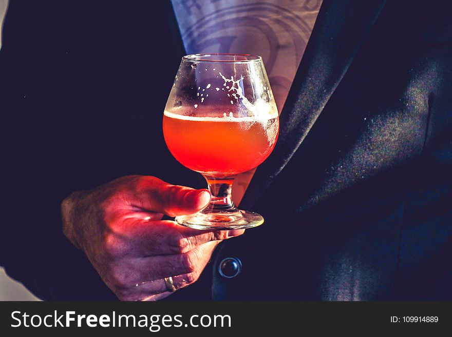 Person Holds Clear Glass Snifter With Red Beverage