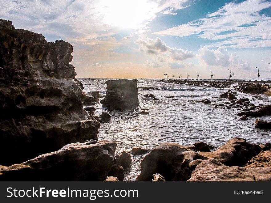 Landscape Photography Of Rocks Surrounded By Body Of Water