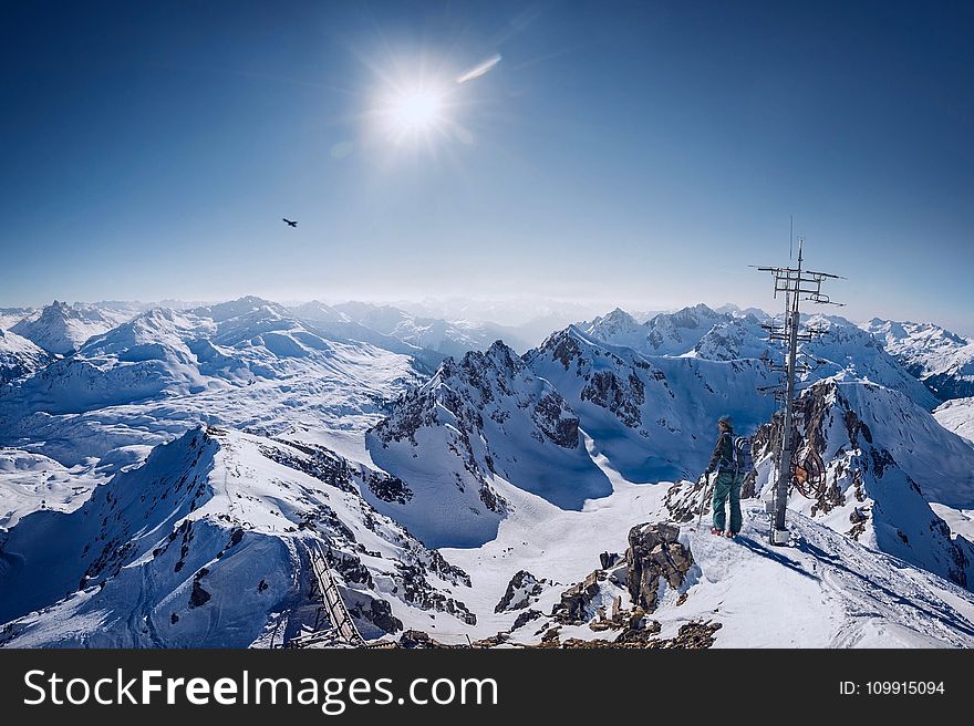 Person on Top of Snow Covered Mountain Under Clear Blue Sky