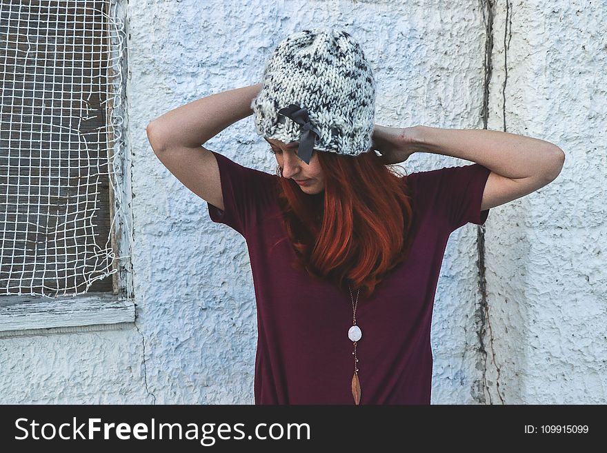 Woman in White and Black Knit Cap Posing Near White Wall