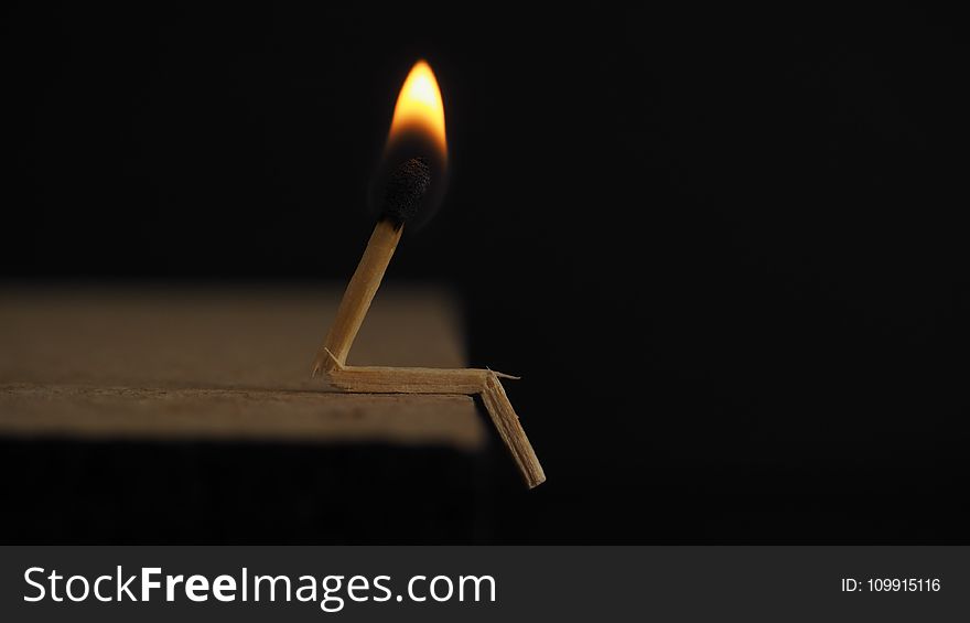 Lighted Matchstick on Brown Wooden Surface