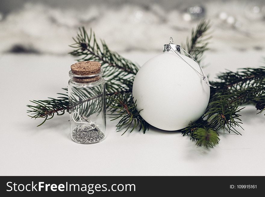 Selective Focus Photography of White Christmas Bauble Beside Bottle With Cork Lid
