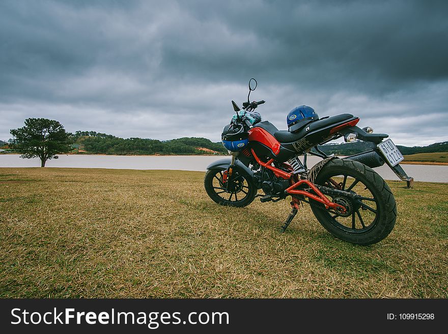 Red and Black Standard Motorcycle on Green Grass Field