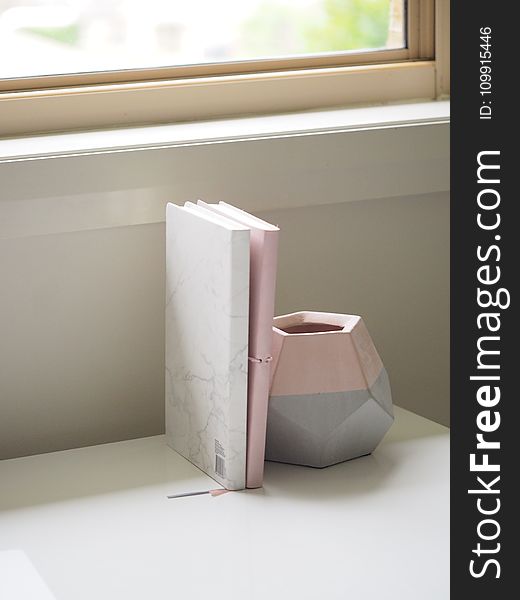 White And Pink Books Piled Beside Pink And Gray Ceramic Vase