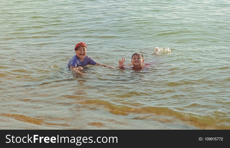 Two Boy on Brown Body of Water