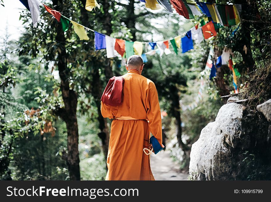 Monk Walking Near Buntings During Day