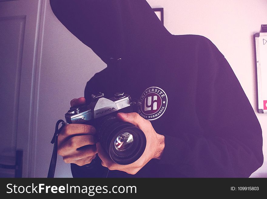 Man Holding Black and Gray Dslr Camera Inside White Wall Paint Room