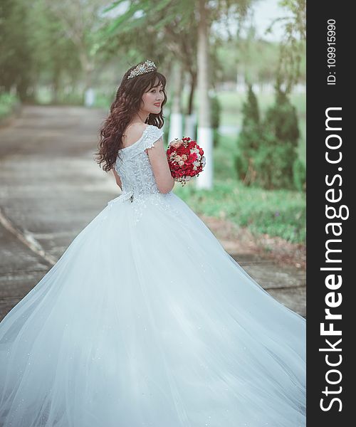 Woman in White Wedding Dress Holding Red Bouquet