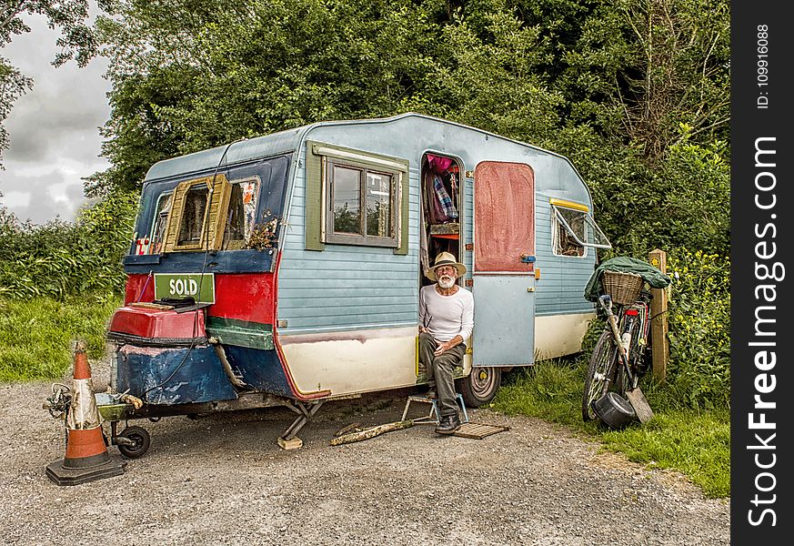 Photo Of A Man In White Long-sleeved Top on Blue And White Pop-up Camper