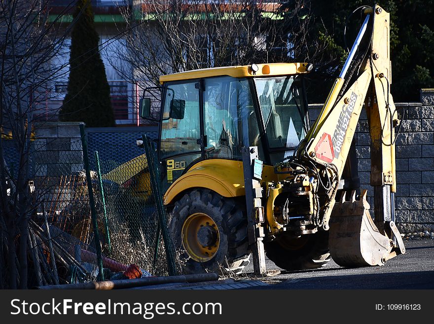 Yellow and Black Backhoe Near the Wire Fence