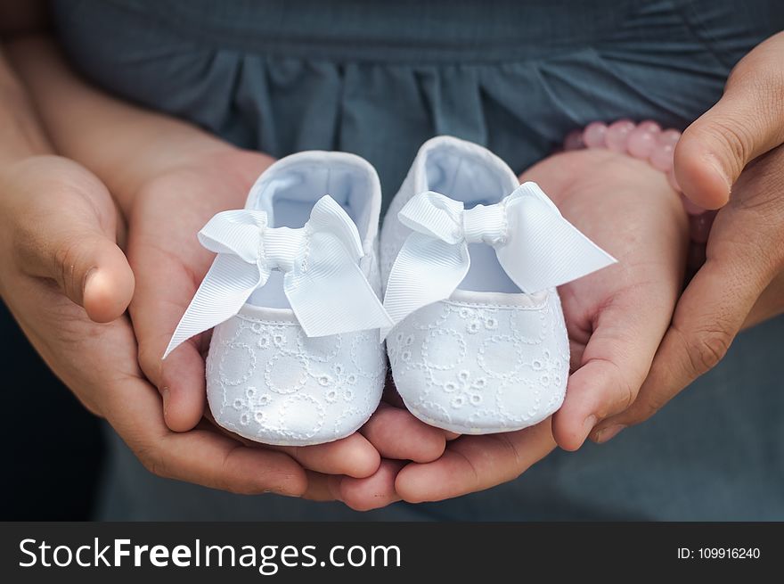 Person Carrying Pair of Baby&#x27;s White Flats